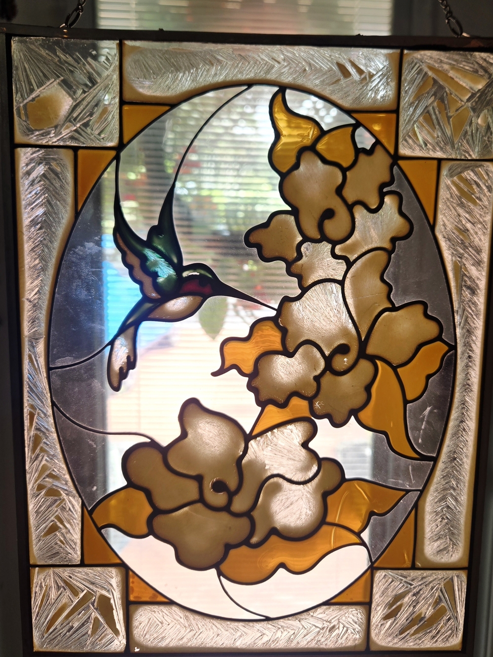 Stained-glass suncatcher panel featuring an oval center with a green hummingbird